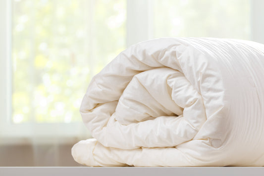 A folded rolls duvet is lying on the dresser against the background of a blurred window. Household.