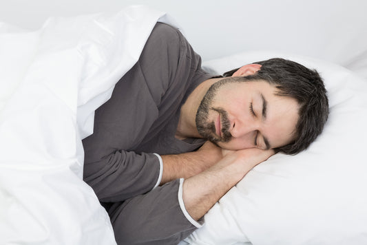 A man peacefully sleeping in bed, resting his head comfortably on a soft pillow.